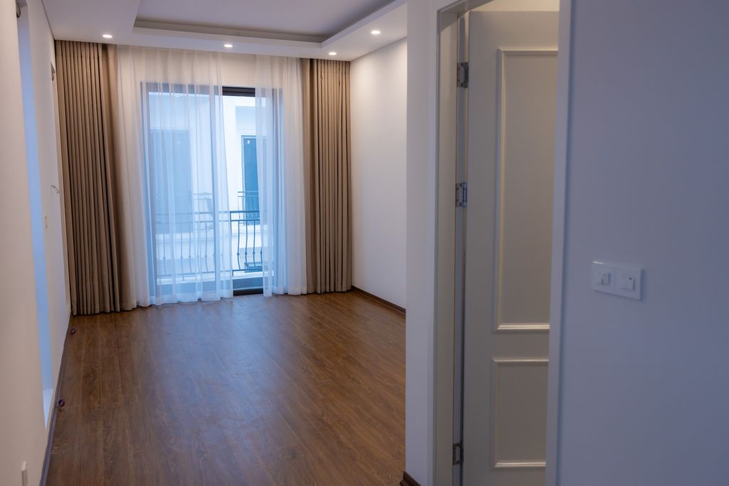 Bright empty room with wooden floor and balcony, ideal for interior design projects.